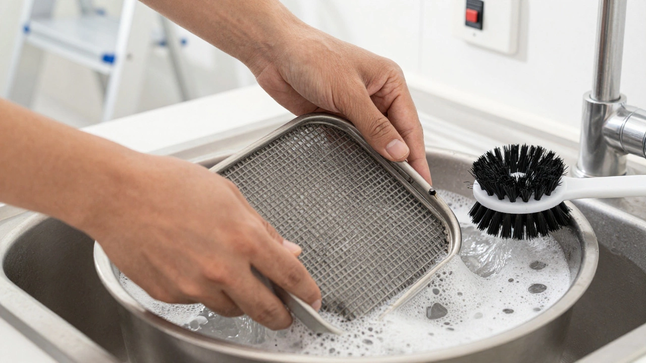 Hands cleaning a greasy extractor fan filter in soapy water near a ladder